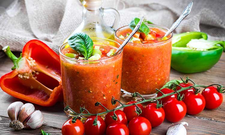 Gazpacho, two glasses of Spanish gazpacho, olive oil, garlic, peppers, and tomatoes.