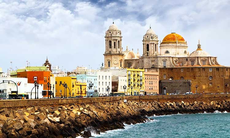 Cadiz Catedral, Cathedral of Cadiz in the cityscape directly on the coast with colorful houses and the sea in the foreground, cathedral with orange round roof, for 10 days spain itinerary