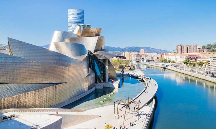 view of the guggenheim museum in bilbao with river on the side, metal building, futuristic