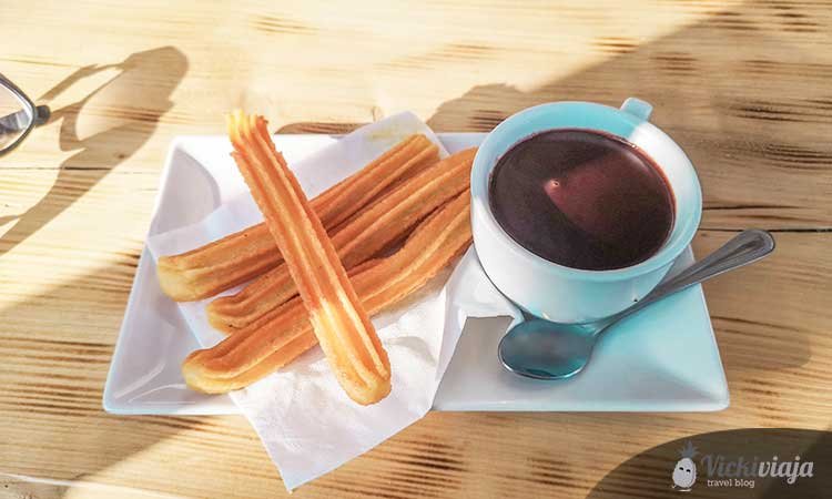 churros con chocolate, spanish pastry with cup full of spanish liquid hot chocolate