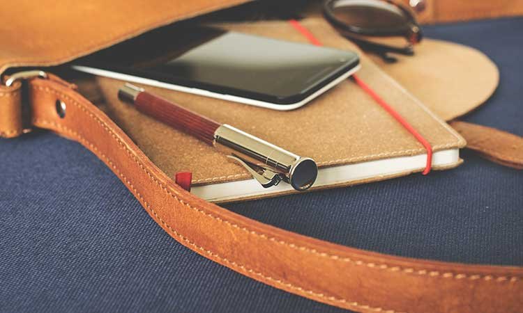 Reisen mit Kugelschreiber im Gepäck, Tasche mit Handy, Kugelschreiber und Notizbuch
