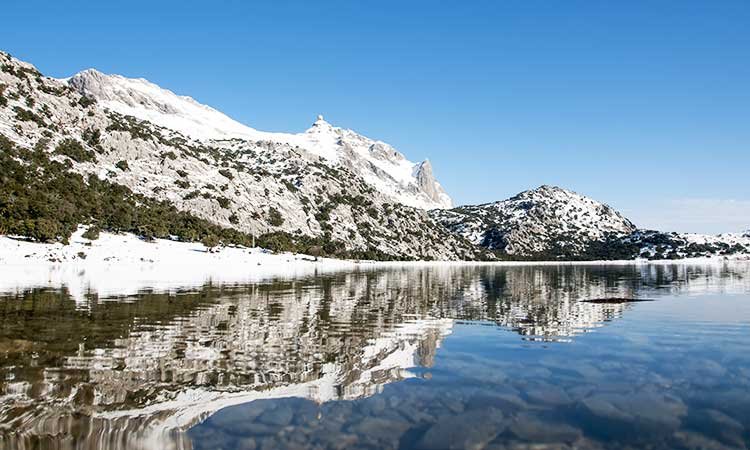 Sierra de Tramuntana, snow, mountain and reflecting lake with blue sky